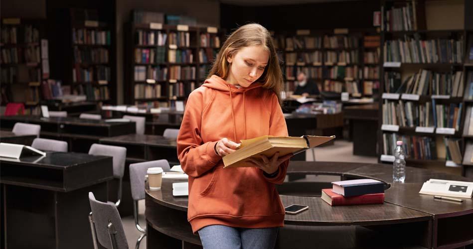 Girl studying VB .Net in library through books